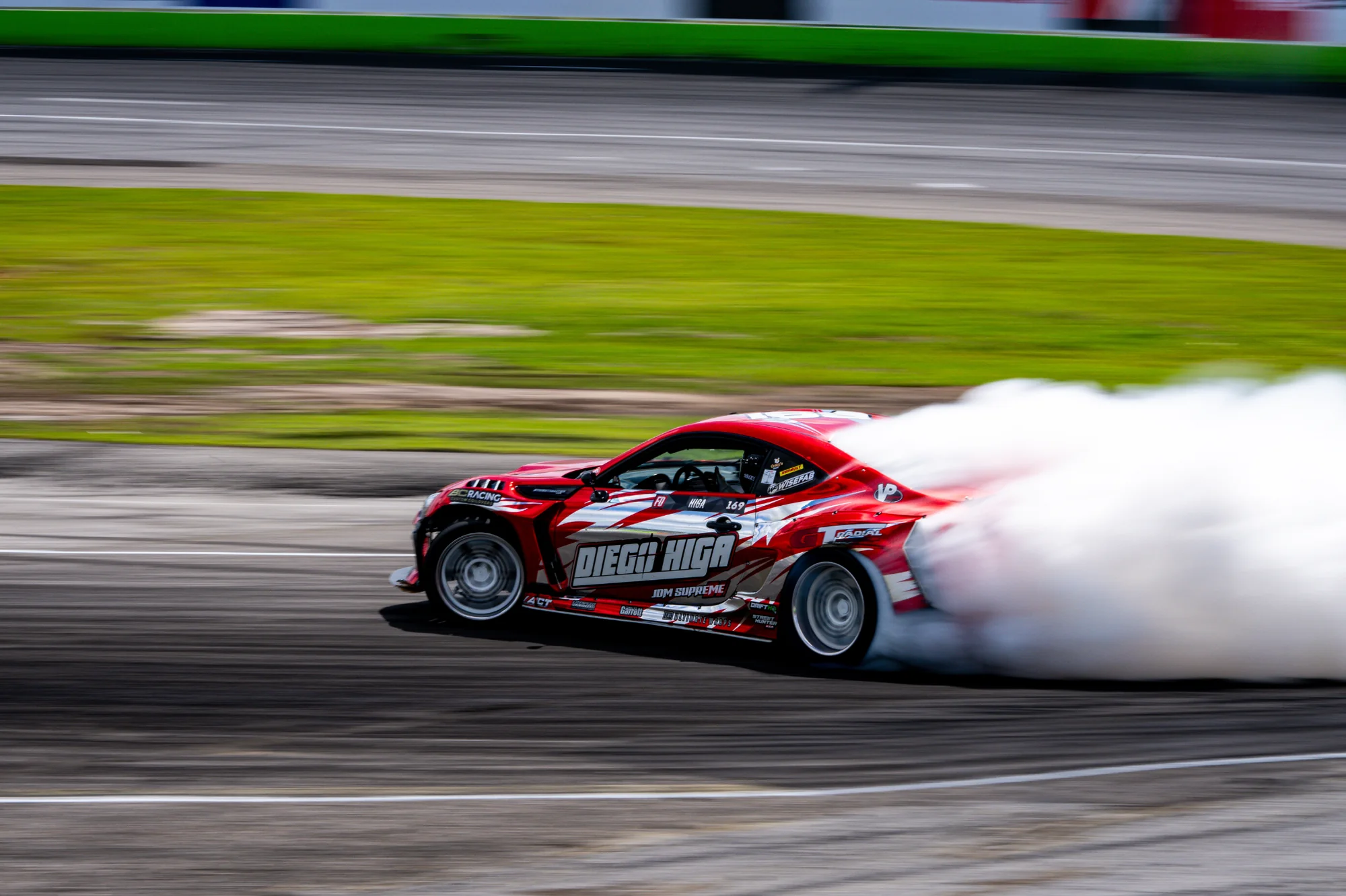Diego Higa in his red Formula Drift race car producing a large cloud of tire smoke