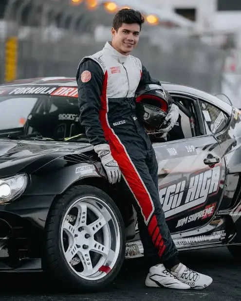 Diego Higa standing beside his professional drift car